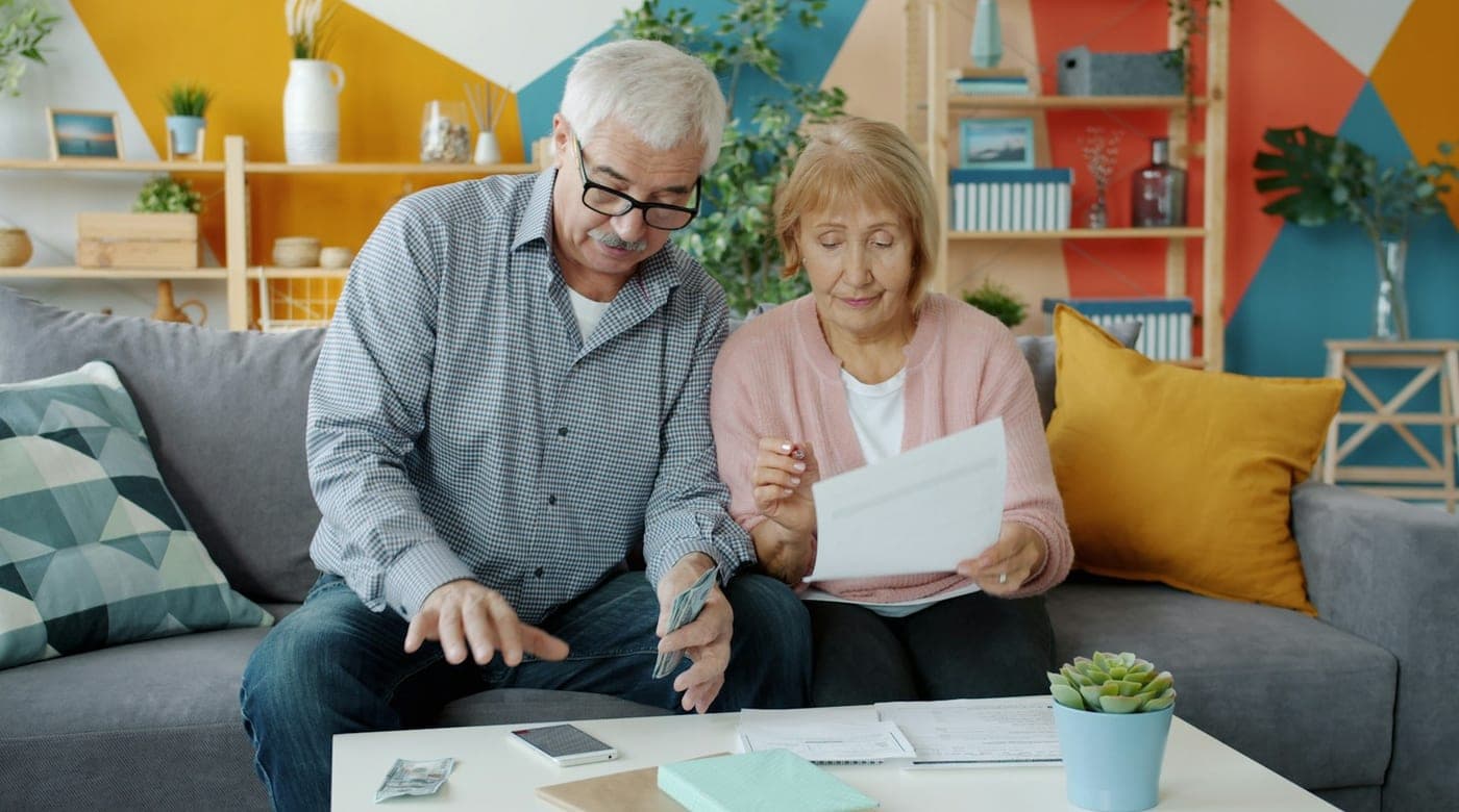 An older couple on a sofa reading a letter together